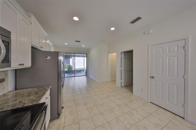 kitchen with white cabinetry, range with electric stovetop, dark stone counters, and light tile patterned flooring