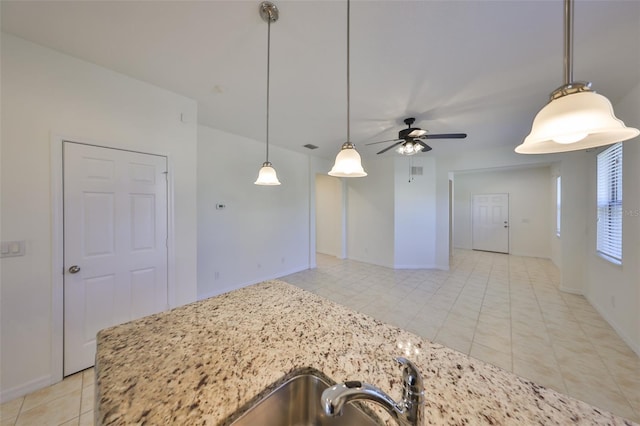 kitchen featuring light stone countertops, pendant lighting, ceiling fan, and light tile patterned floors