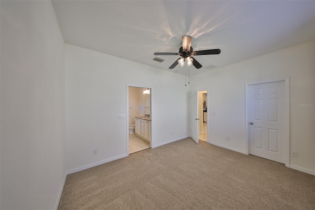 unfurnished bedroom featuring ensuite bathroom, light colored carpet, and ceiling fan