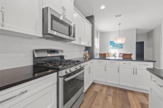 kitchen with pendant lighting, appliances with stainless steel finishes, and white cabinets