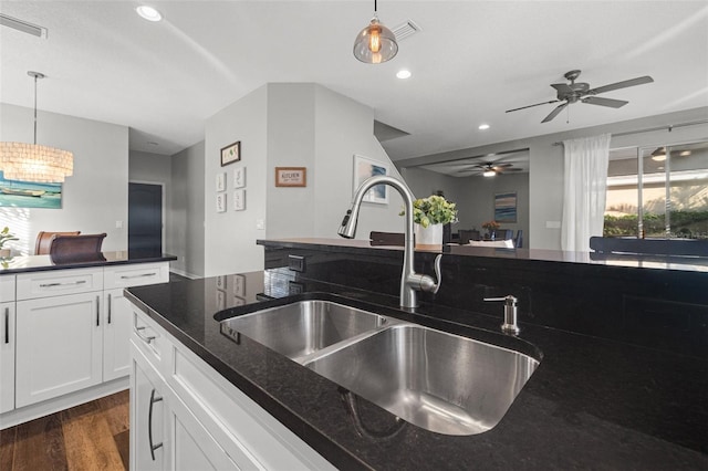 kitchen featuring dark stone counters, decorative light fixtures, sink, and white cabinets