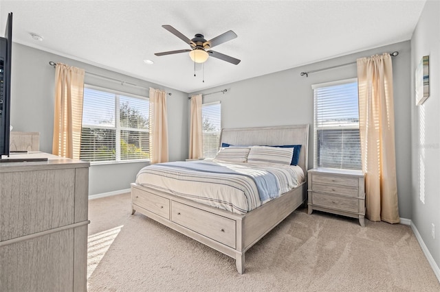 bedroom featuring light carpet, a textured ceiling, and ceiling fan