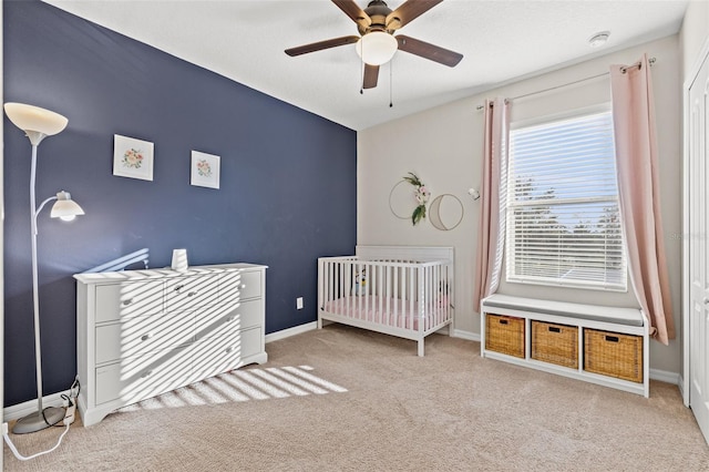 carpeted bedroom with a nursery area and ceiling fan