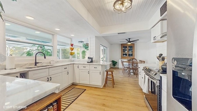 kitchen featuring sink, white cabinets, kitchen peninsula, stainless steel appliances, and light wood-type flooring