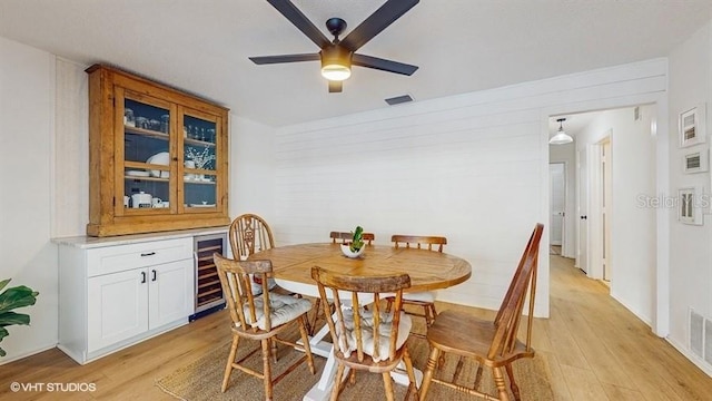 dining space featuring ceiling fan, beverage cooler, and light wood-type flooring