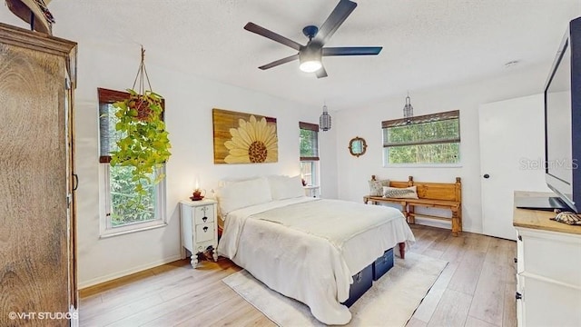 bedroom with ceiling fan, light hardwood / wood-style flooring, and a textured ceiling