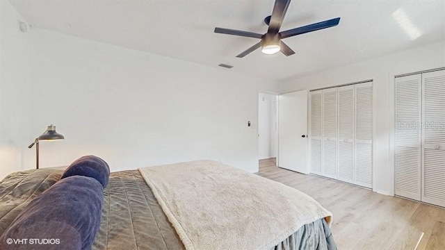 bedroom featuring multiple closets, wood-type flooring, and ceiling fan