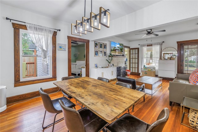 dining area featuring a fireplace, wood-type flooring, and ceiling fan