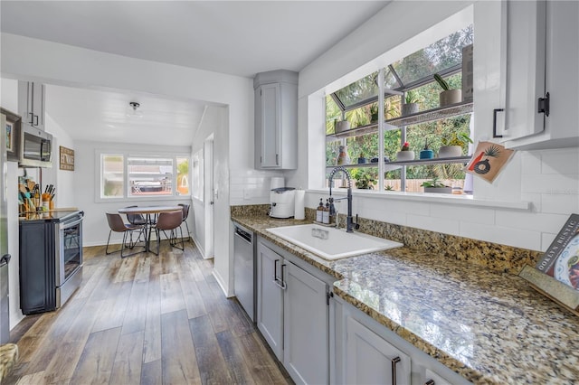 kitchen with stone countertops, sink, dark hardwood / wood-style floors, and appliances with stainless steel finishes