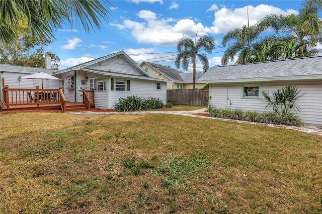 back of property with a deck and a lawn