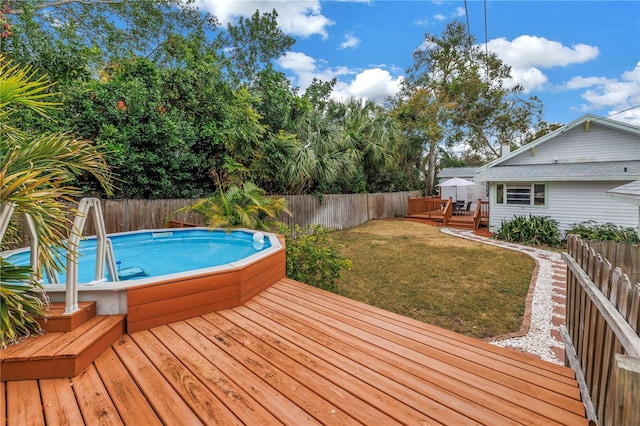 deck featuring a fenced in pool and a yard