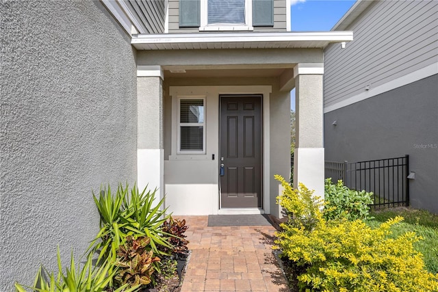 doorway to property with fence and stucco siding