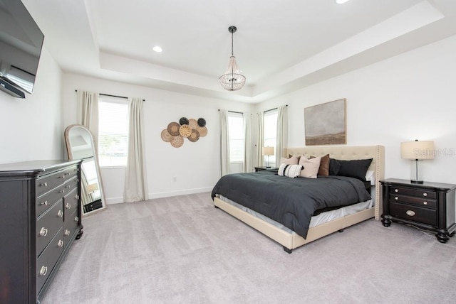 bedroom featuring light colored carpet, a raised ceiling, and multiple windows