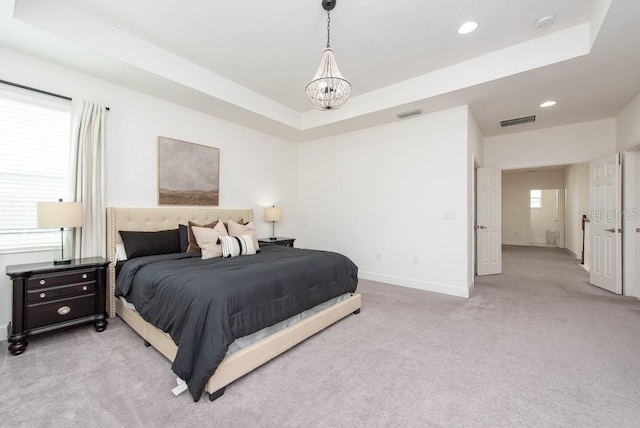 carpeted bedroom featuring a chandelier and a raised ceiling