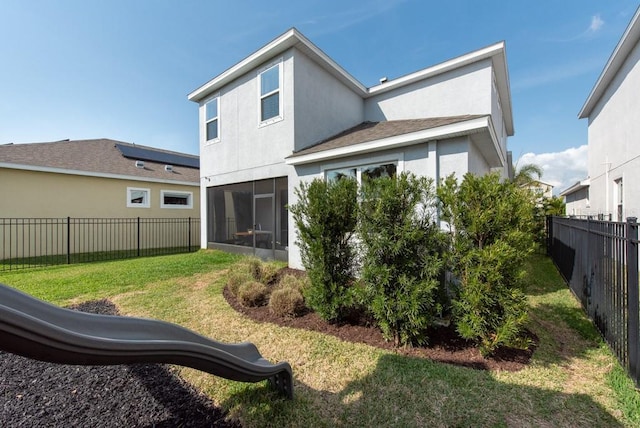 rear view of house featuring a sunroom and a lawn