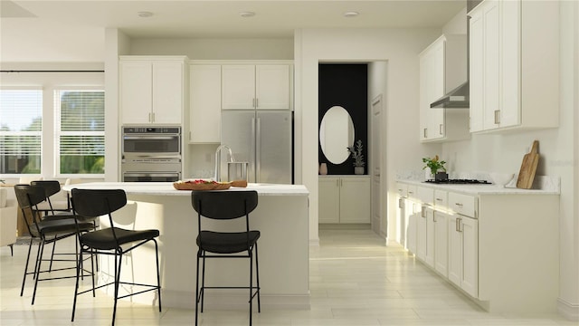 kitchen with white cabinetry, appliances with stainless steel finishes, a kitchen bar, and an island with sink