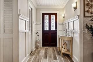 doorway with ornamental molding and wood-type flooring