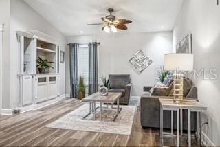 living area with wood-type flooring and ceiling fan