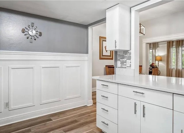 kitchen with hardwood / wood-style flooring, white cabinets, and backsplash