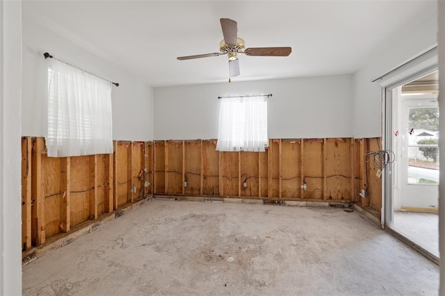 unfurnished room featuring ceiling fan and wooden walls