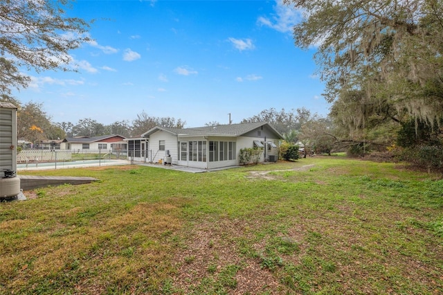 back of house with a pool, a sunroom, a yard, and a patio