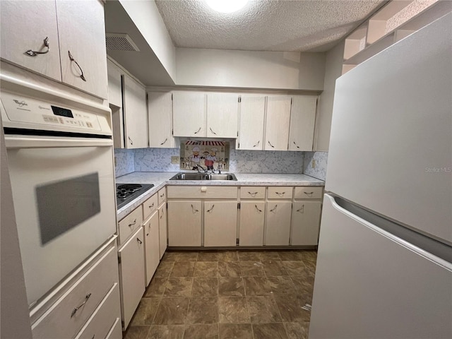 kitchen with tasteful backsplash, sink, white appliances, and a textured ceiling