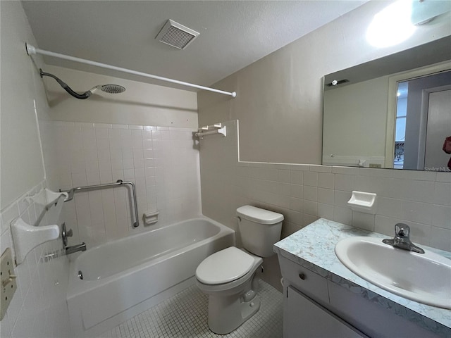 full bathroom featuring toilet, tiled shower / bath, tile walls, vanity, and tile patterned flooring