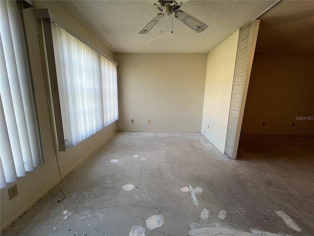 unfurnished room with ceiling fan and a textured ceiling