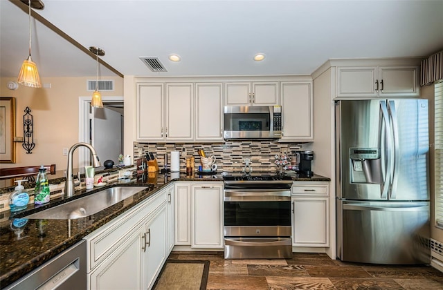 kitchen with decorative light fixtures, white cabinetry, sink, dark stone counters, and stainless steel appliances