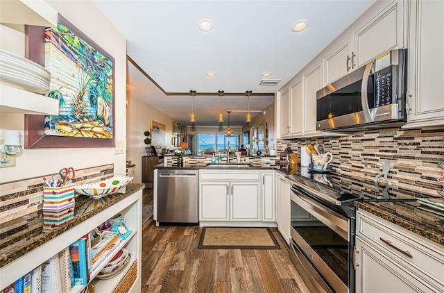 kitchen with white cabinets, dark hardwood / wood-style flooring, hanging light fixtures, kitchen peninsula, and stainless steel appliances