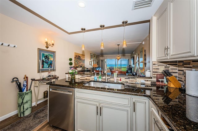 kitchen with sink, tasteful backsplash, dark stone countertops, dishwasher, and pendant lighting