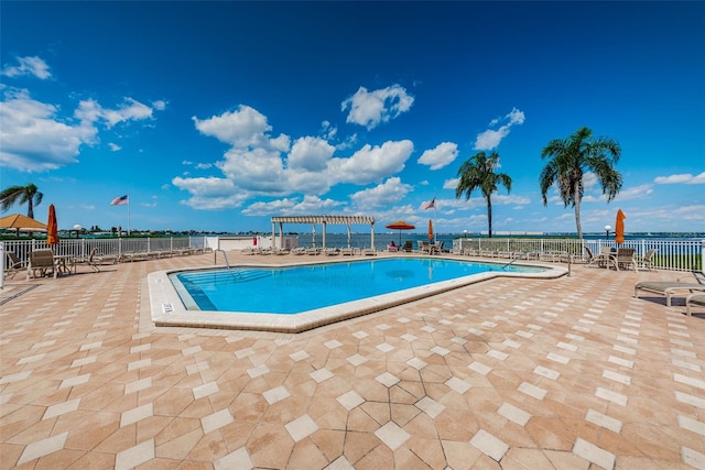 view of swimming pool with a water view, a pergola, and a patio area