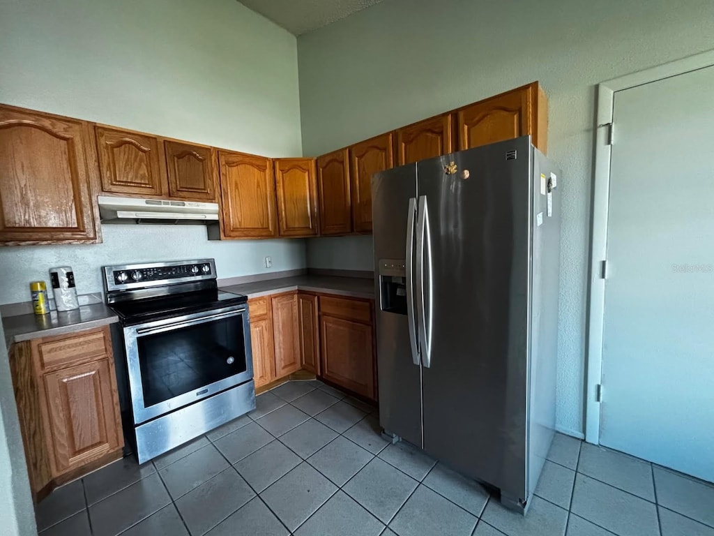 kitchen with a towering ceiling, tile patterned floors, and appliances with stainless steel finishes