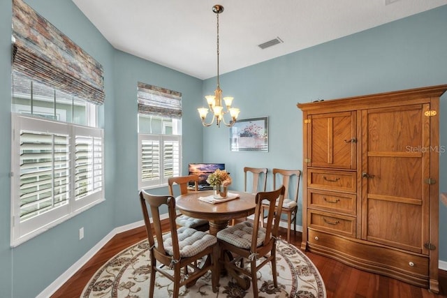 dining space with dark hardwood / wood-style floors and a notable chandelier