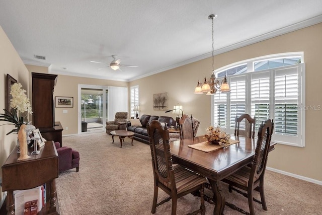 carpeted dining room featuring ornamental molding and ceiling fan with notable chandelier