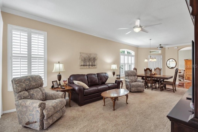 living room with ornamental molding, ceiling fan with notable chandelier, and light colored carpet