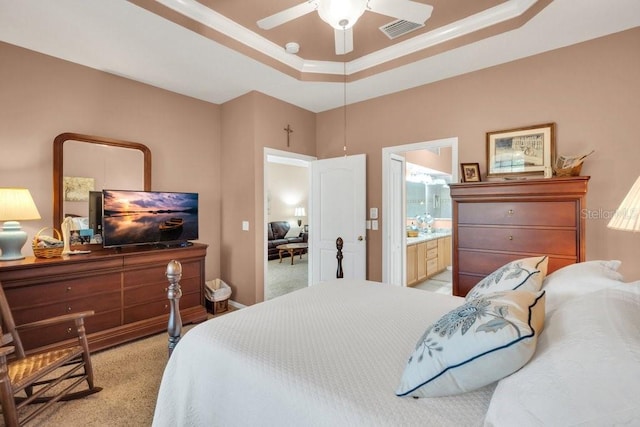 carpeted bedroom featuring ornamental molding, ceiling fan, ensuite bath, and a tray ceiling