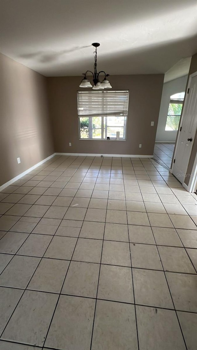 spare room featuring a chandelier and light tile patterned floors