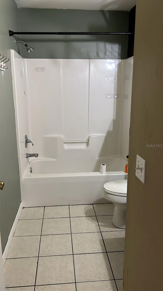 bathroom featuring tile patterned flooring, bathing tub / shower combination, and toilet