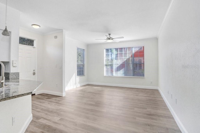 unfurnished living room with ornamental molding, light hardwood / wood-style floors, and ceiling fan