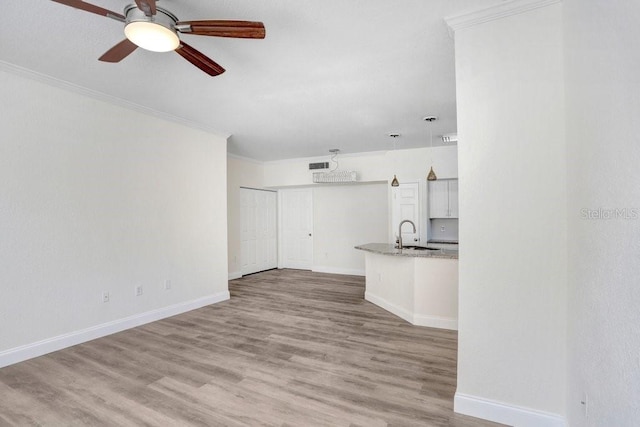 unfurnished living room featuring crown molding, sink, ceiling fan, and light hardwood / wood-style floors