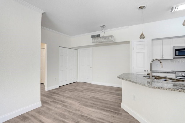 kitchen with appliances with stainless steel finishes, sink, white cabinets, ornamental molding, and light stone countertops