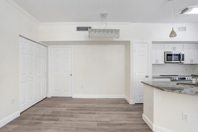 kitchen with stone counters, pendant lighting, white cabinets, ornamental molding, and stainless steel appliances