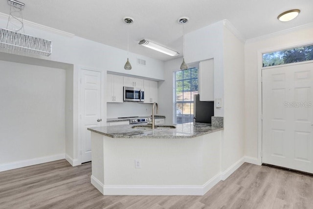 kitchen with pendant lighting, kitchen peninsula, sink, and white cabinets