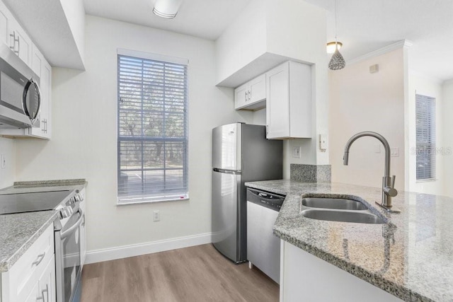 kitchen with pendant lighting, sink, appliances with stainless steel finishes, light stone counters, and white cabinets