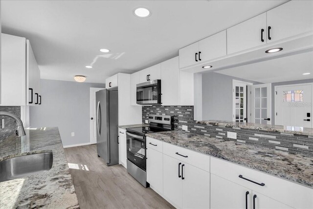 kitchen featuring appliances with stainless steel finishes, tasteful backsplash, sink, white cabinets, and light stone counters