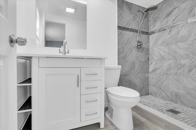 bathroom with vanity, toilet, and a tile shower