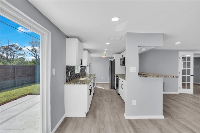 kitchen with sink, appliances with stainless steel finishes, white cabinets, decorative backsplash, and dark stone counters