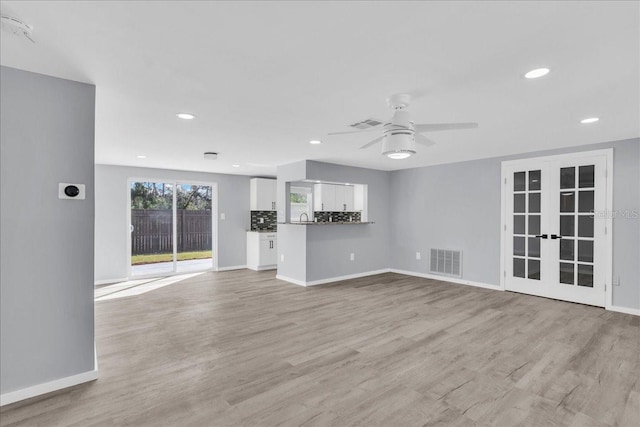 unfurnished living room with ceiling fan, light wood-type flooring, and french doors