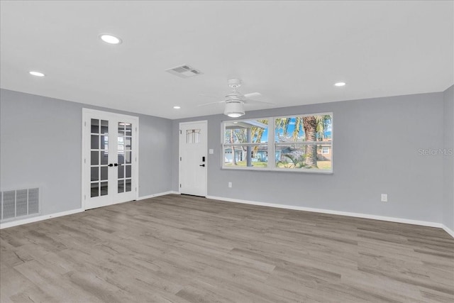 unfurnished living room with ceiling fan, light wood-type flooring, and french doors